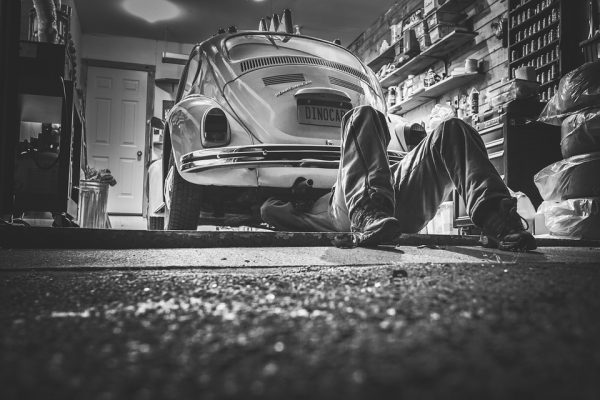 Black and white image of a mechanic under a car